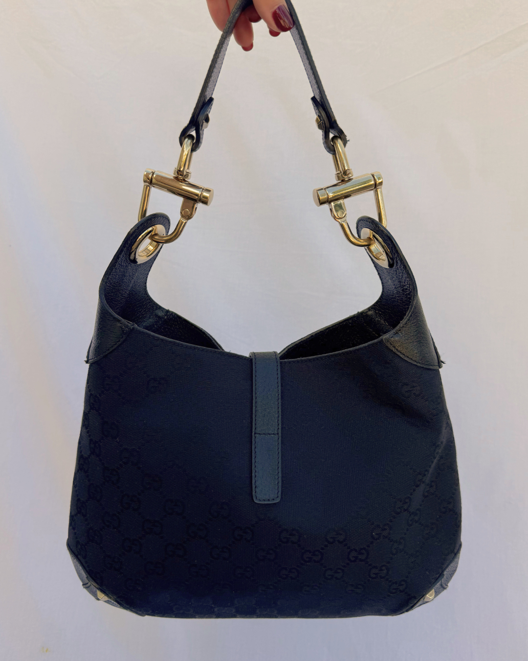Black textured handbag with gold hardware on a white background