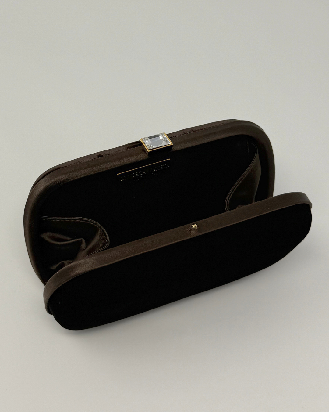 Brown velvet vintage clutch bag with a decorative clasp on a white background