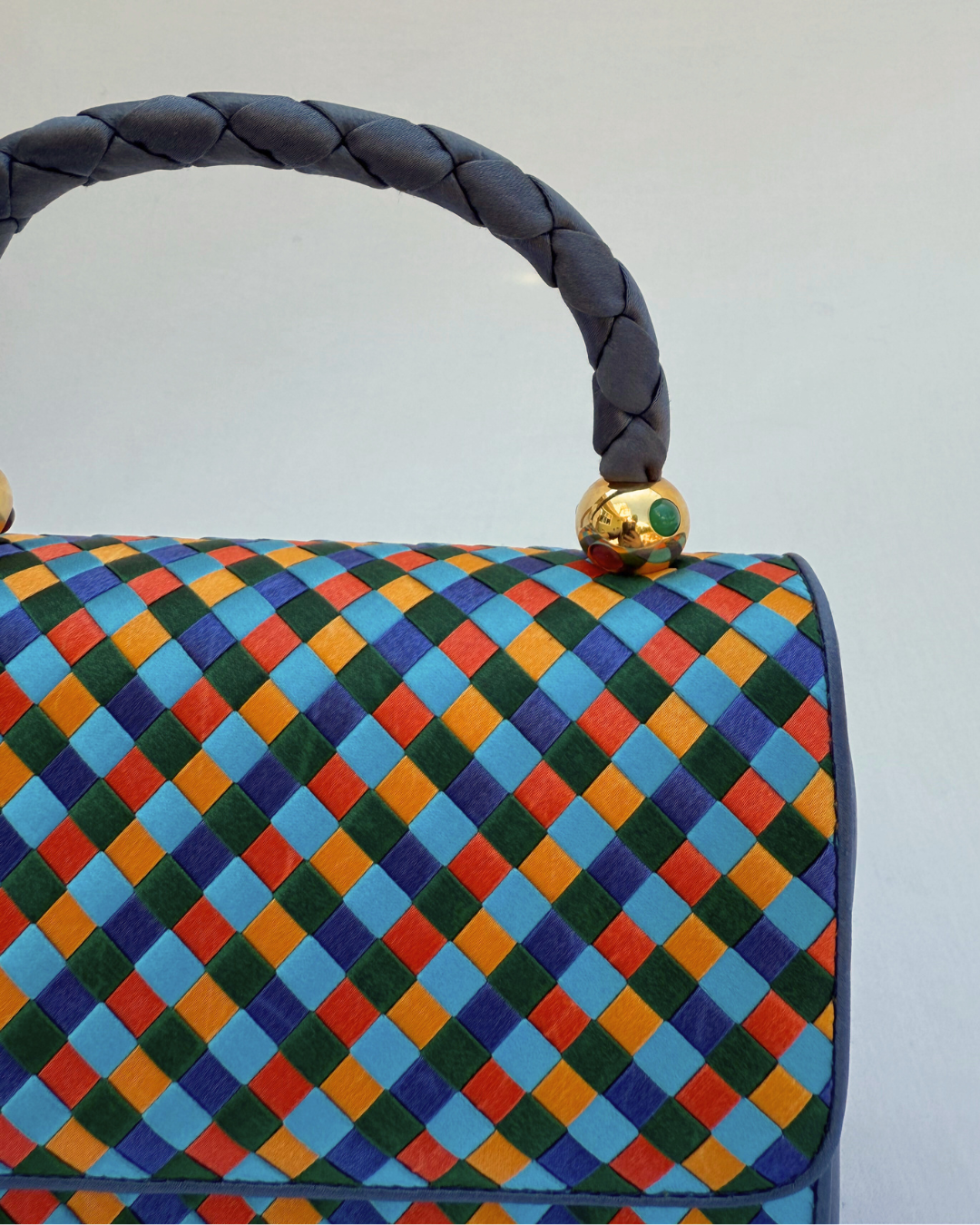 Colorful checkered handbag with braided handle on a white background close up of side angle