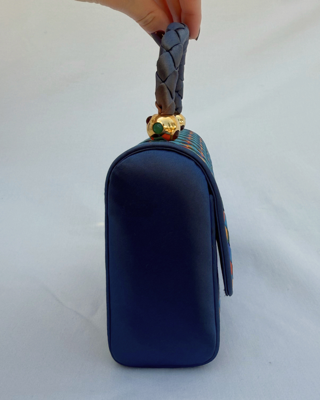 Navy blue pouch with braided handle on a white background side view