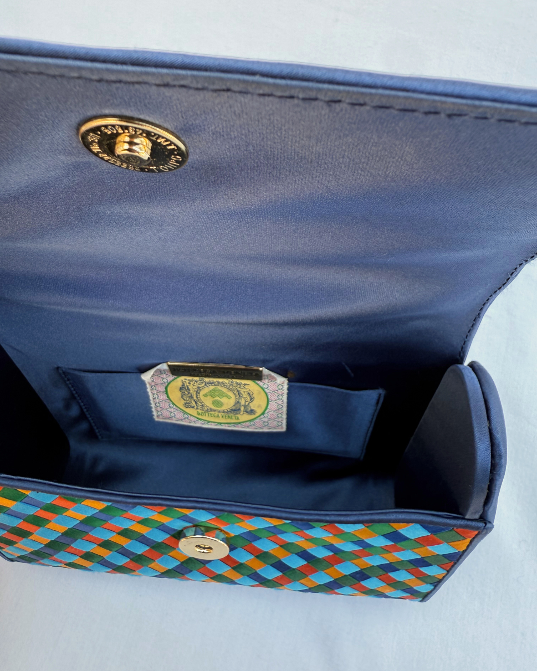 Multicolor handbag with a colorful interior and gold emblem on a white background