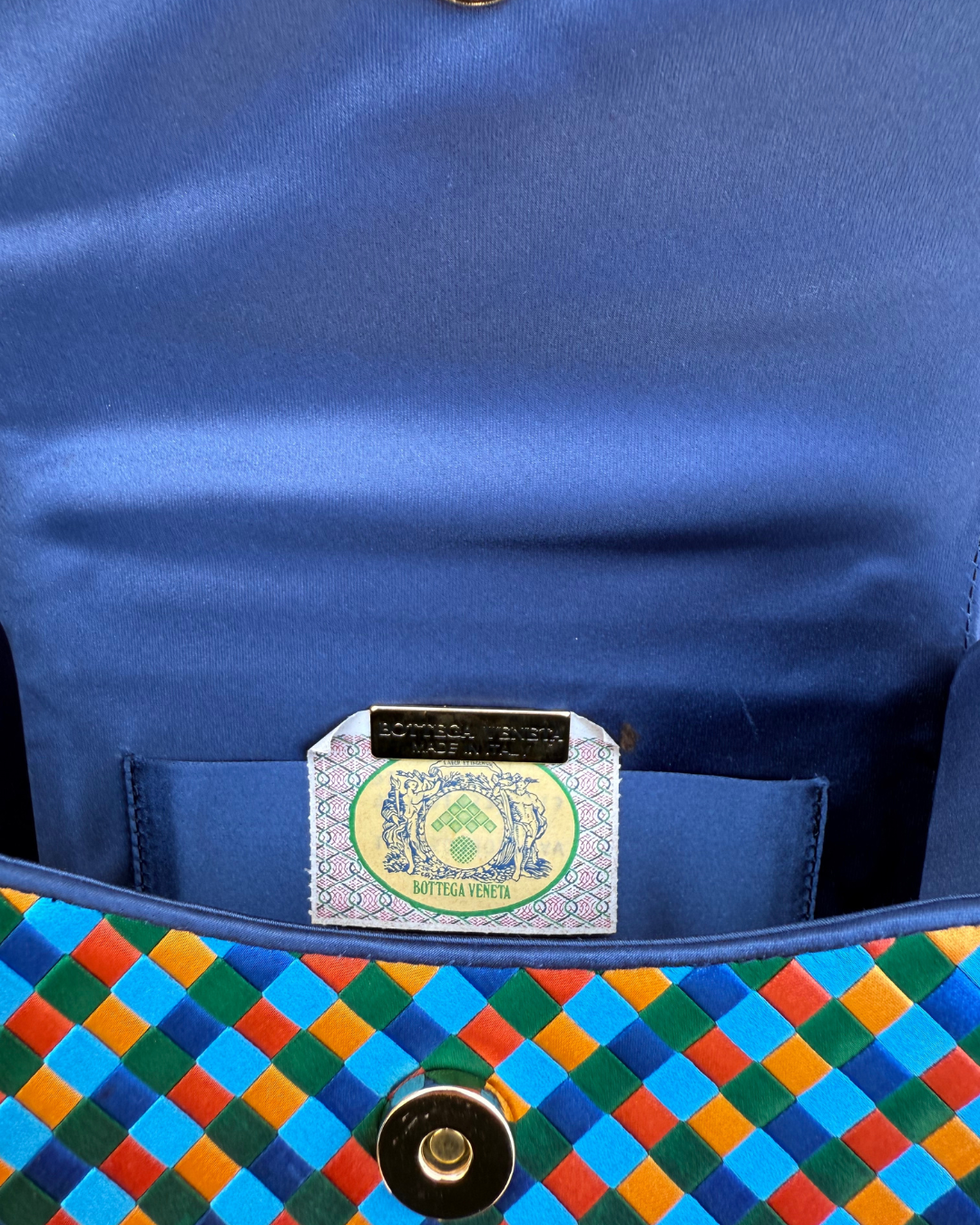 Close-up of a blue bag with a colorful woven pattern and a visible Bottega Veneta brand label.