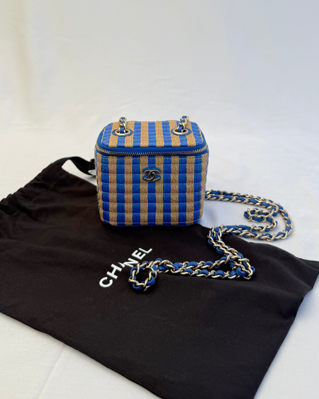 Front view of Chanel 2021 Raffia Mini Vanity Case blue and raffia striped leather pre-loved vintage handbag original Chanel dust cover with a white background
