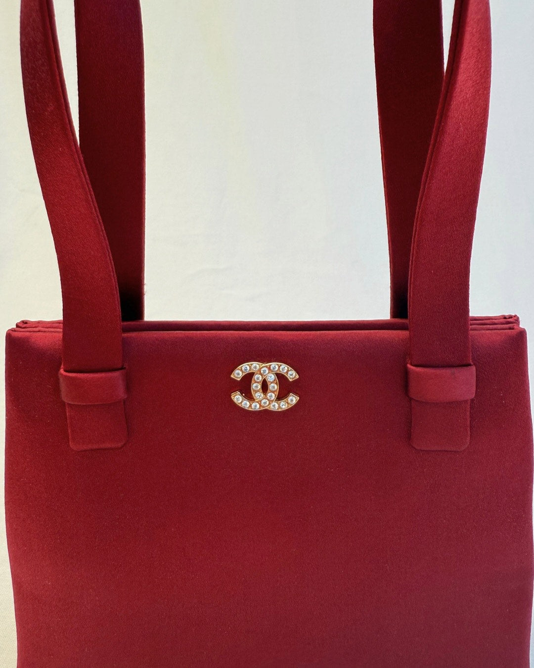 Front detail view of Interlocking CC logo of Chanel Rare Vintage 1990's Red Satin Evening Bag vintage handbag on white background