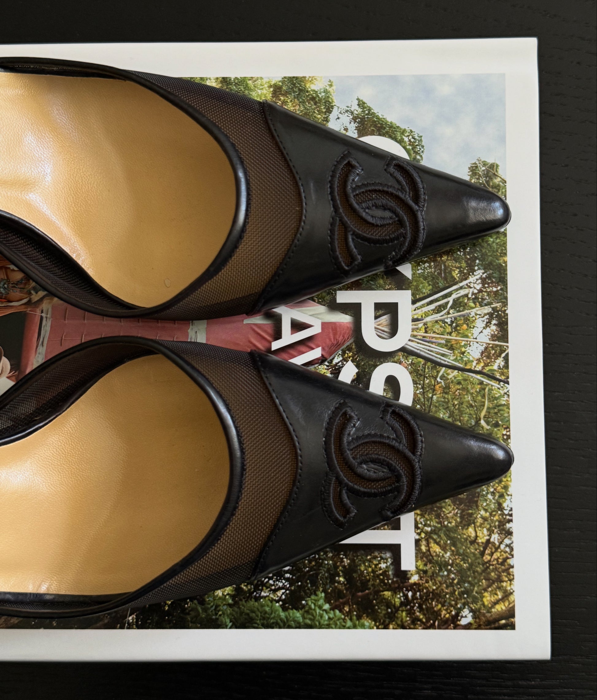 Pair of black and beige high-heeled shoes with Chanel logo on a magazine cover background