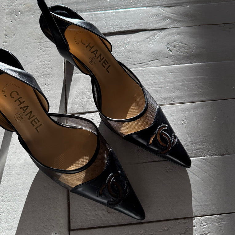 Black high-heeled shoes with Chanel logo on a wooden floor