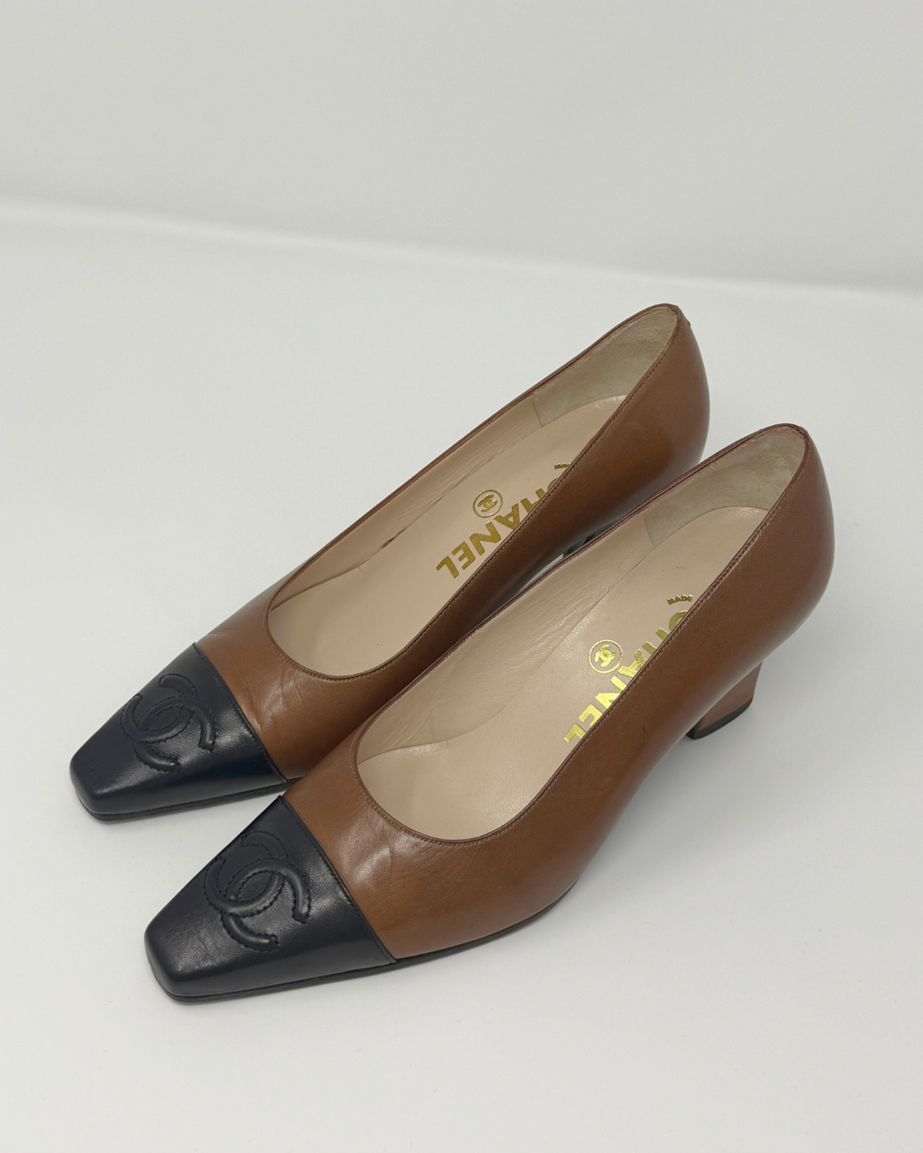 Pair of black and brown shoes with a visible brand logo on a white background