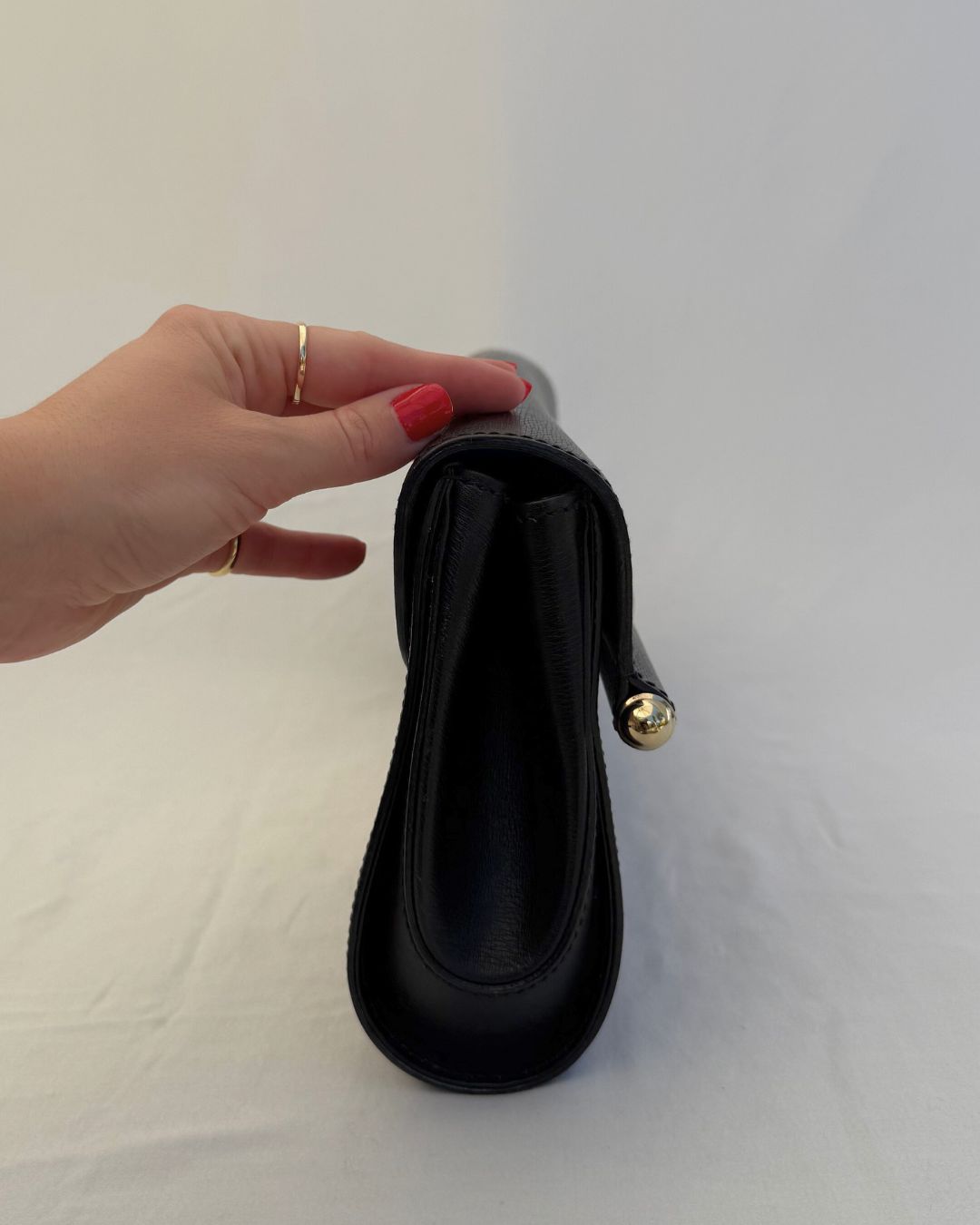 Side detail view of Gucci Vintage Black Leather & Bamboo Clutch with gold hardware on white background