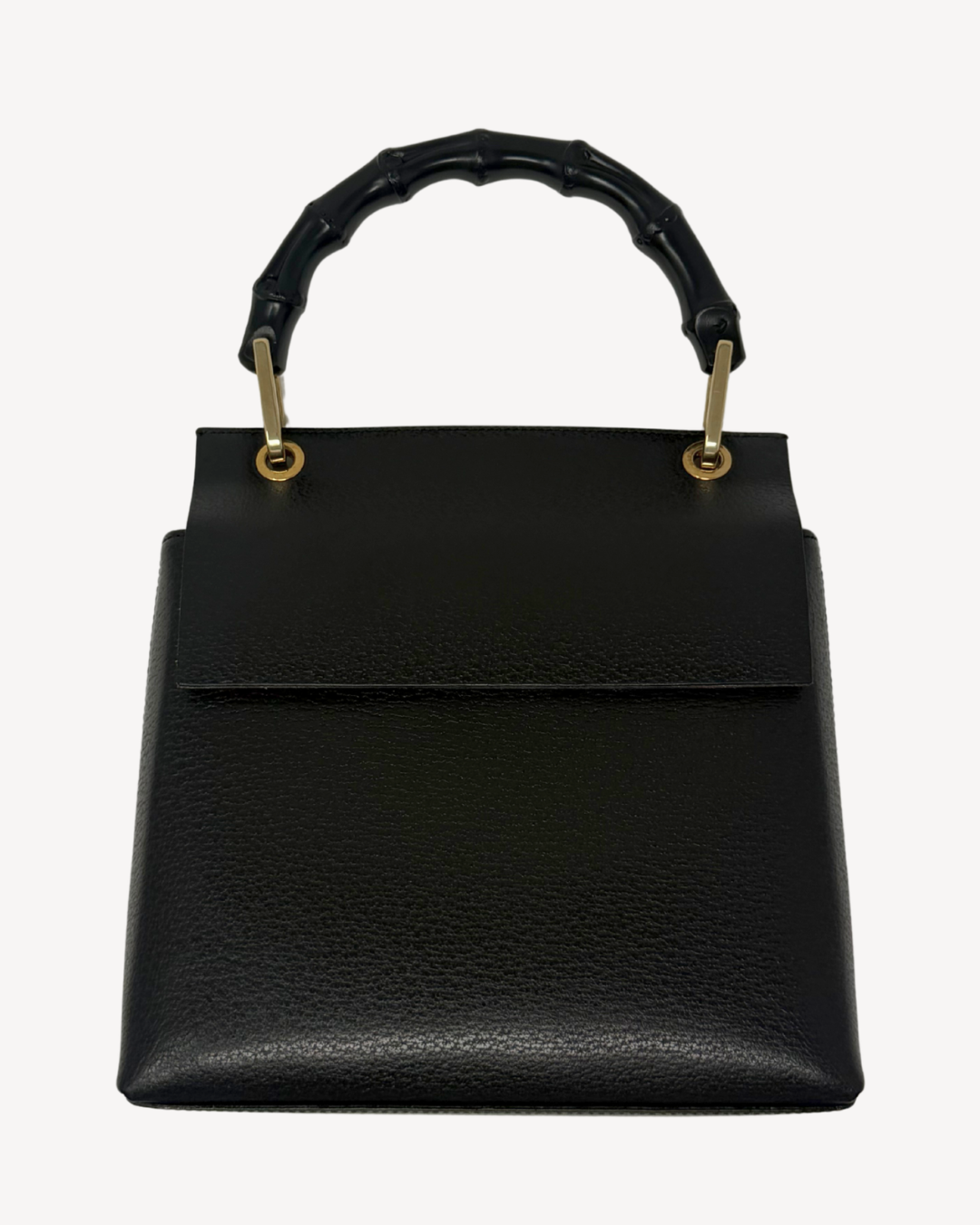 A black pebbled leather handbag with a structured rectangular shape, a top flap, and a curved bamboo-style top handle attached with gold-tone hardware, shown against a plain light background.
