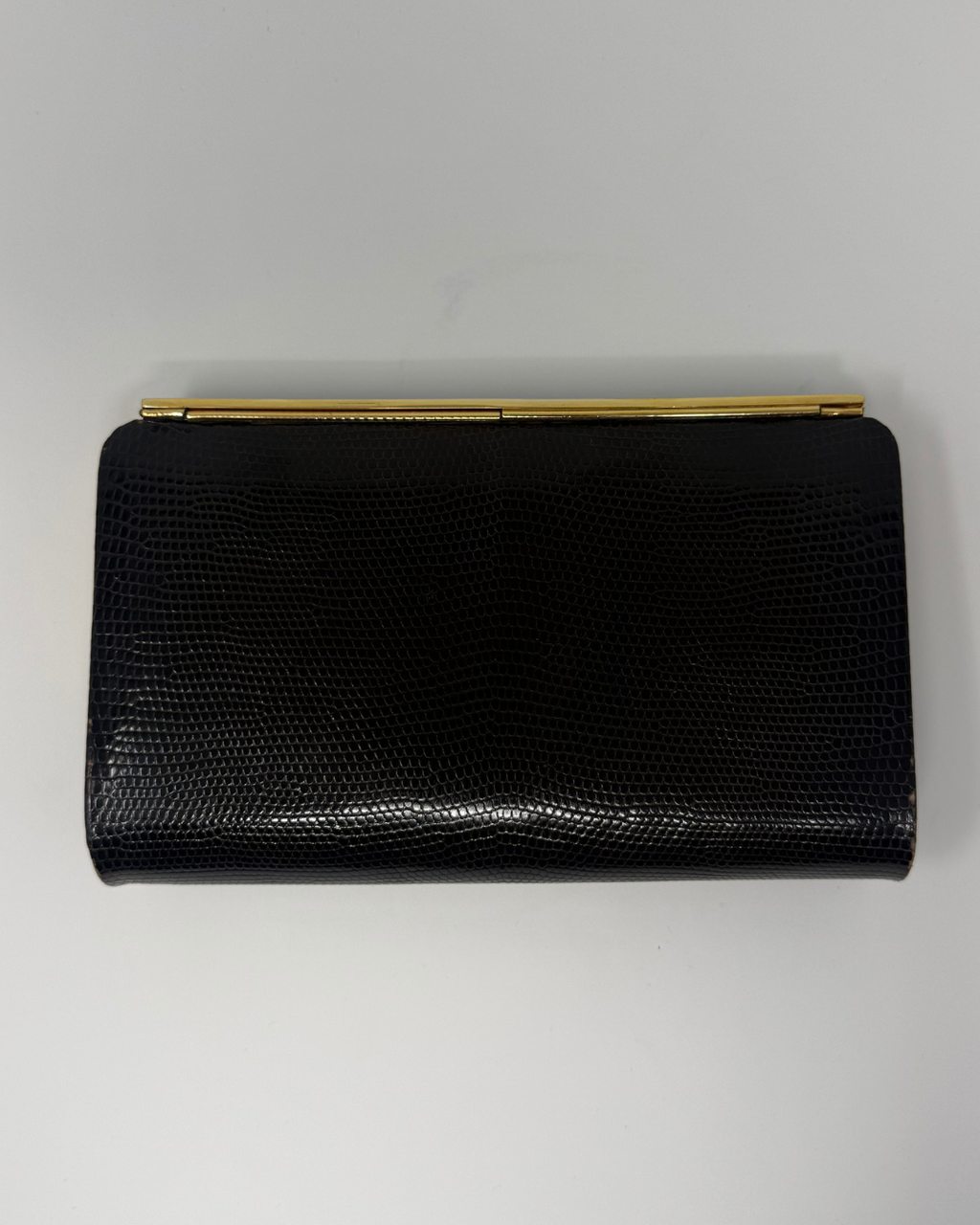 A brown textured clutch purse with a gold-tone metal bar clasp, displayed flat against a light gray background.