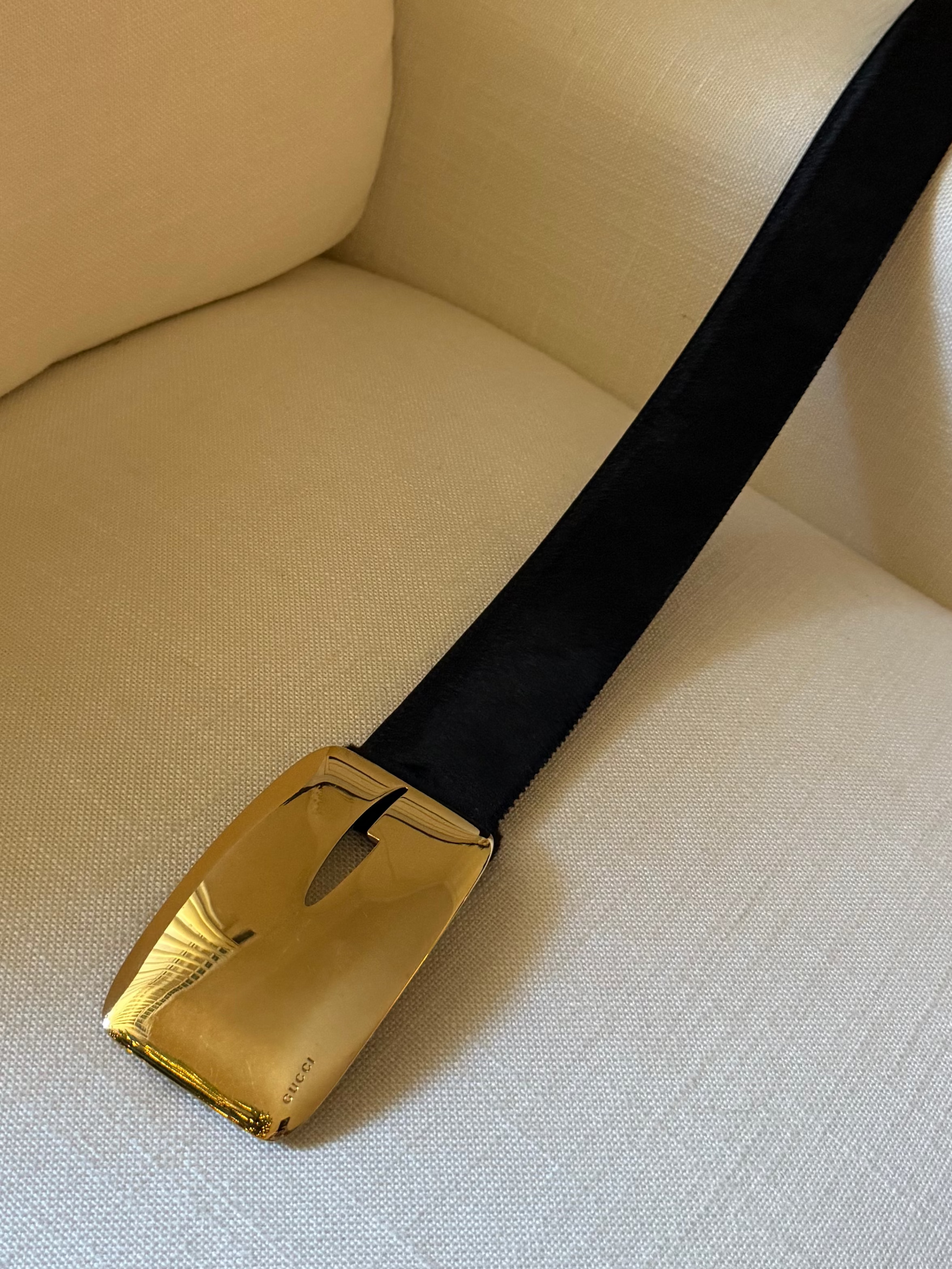 Black belt with a gold buckle on a beige sofa
