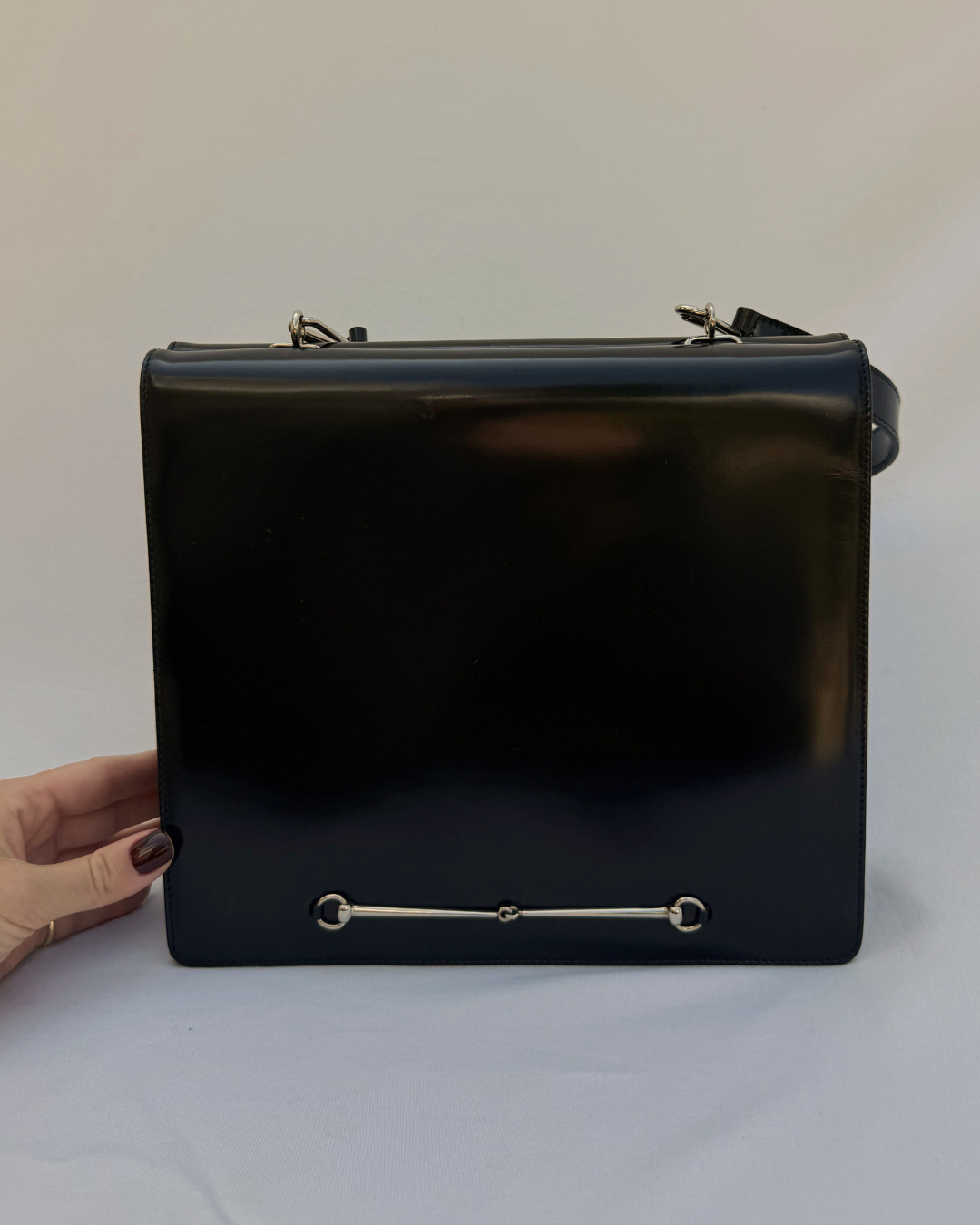 Black leather vintage Gucci by Tom Ford handbag held by a hand on a white background front view