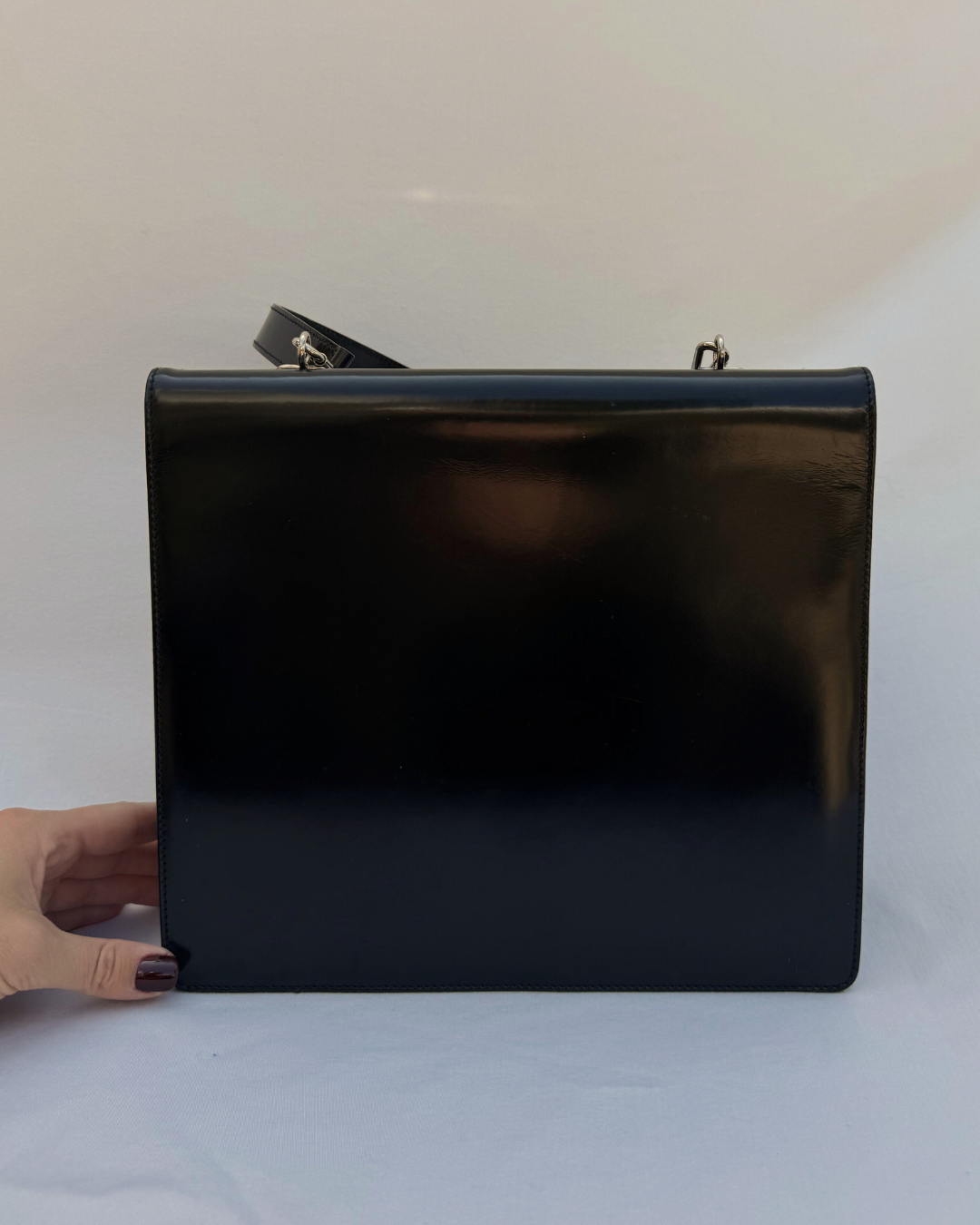 Black leather Gucci by Tom Ford vintage handbag held by a hand on a white background back view