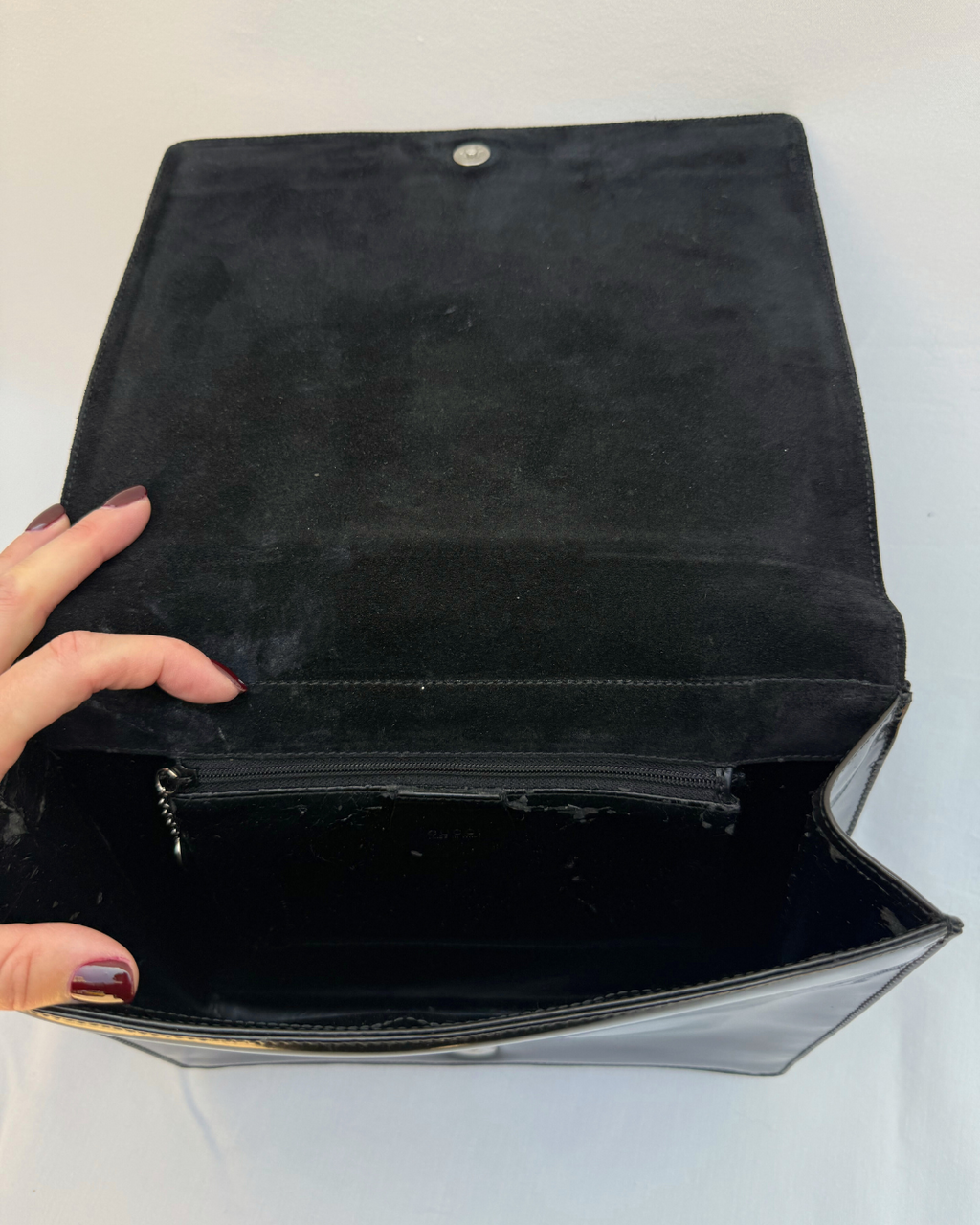 Black leather Gucci by Tom Ford vintage handbag held open by a hand on a white background inside view