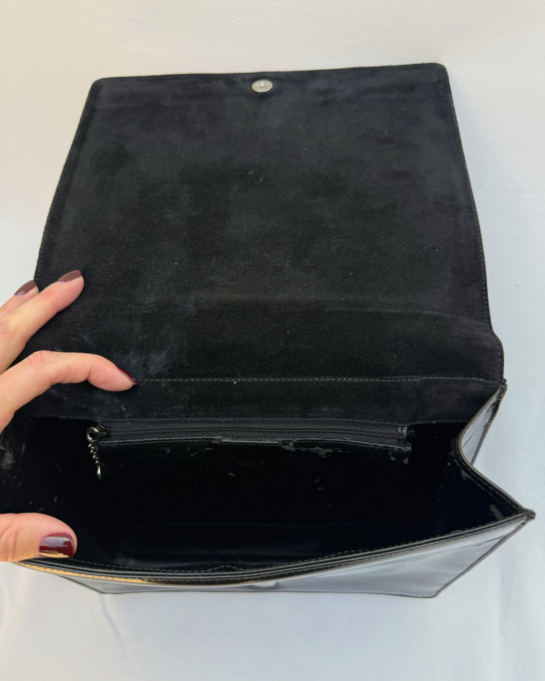 Black leather Gucci by Tom Ford vintage handbag held open by a hand on a white background inside view