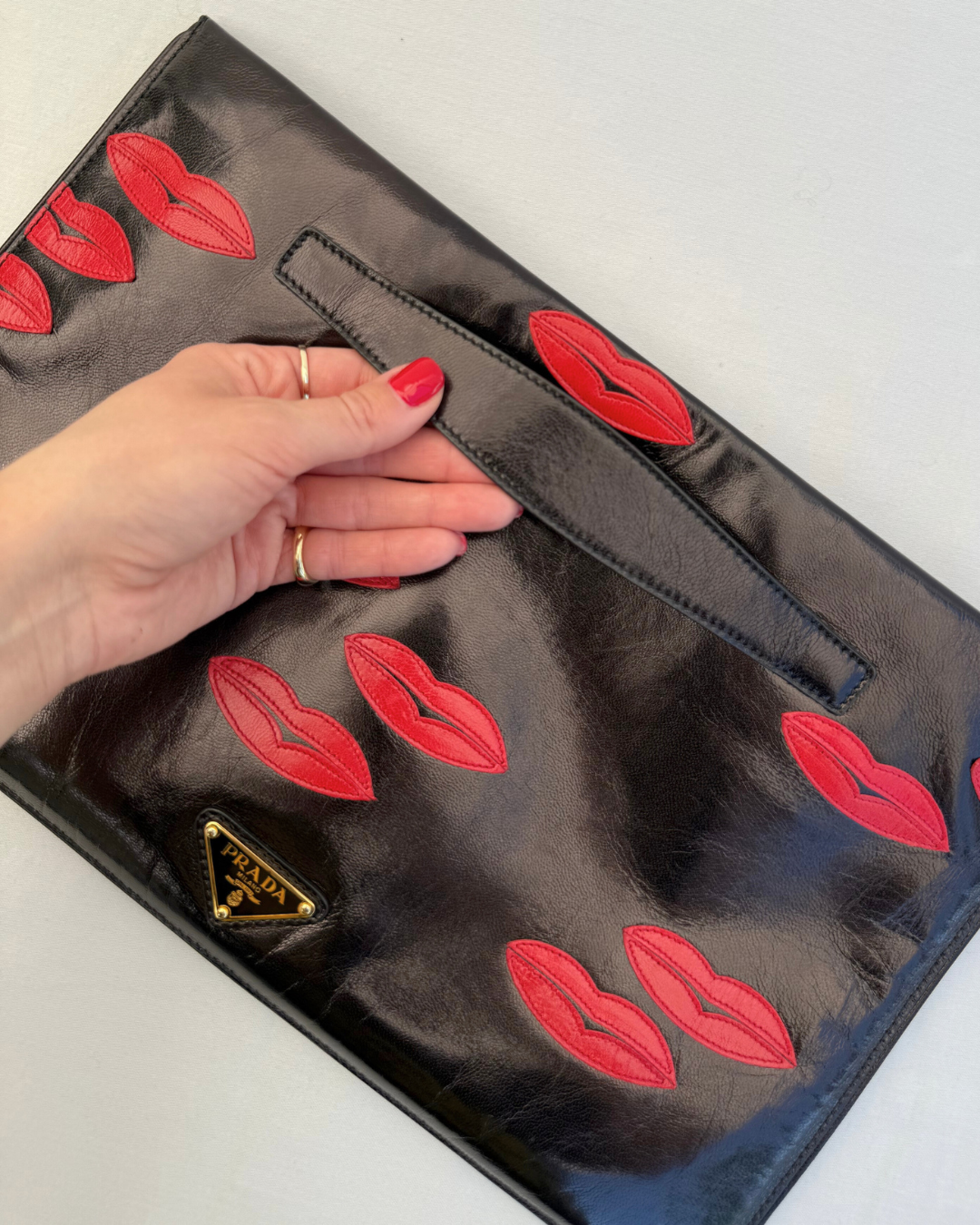 Top view and handle view of Prada Madras Leather Lips Clutch red and black lips graphic vintage handbag
