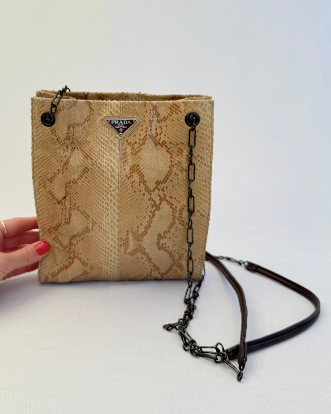 Front view with model hand of Prada Rare Vintage Enameled Metal Triangle Snakeskin Shoulder Bag on white background