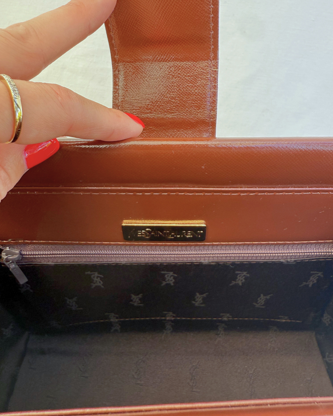 Inside view of the Saint Laurent Vintage Brown Leather Shoulder Bag vintage handbag on white background with black satin lining