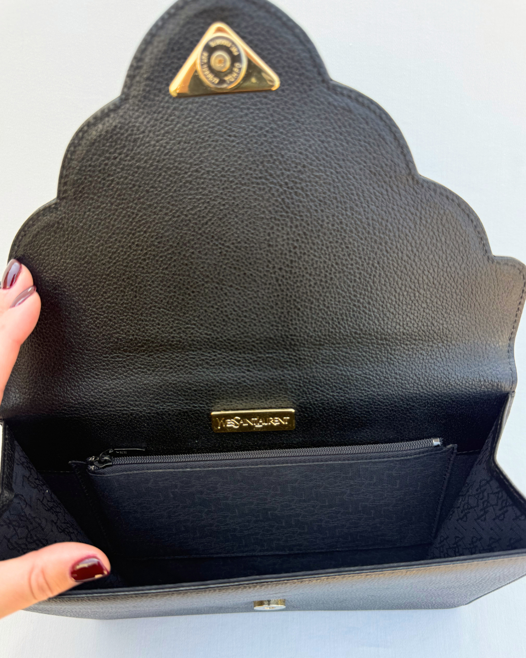 Black handbag with gold logo on a light gray background inside view satin lining